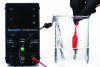 Fig 5. Set-up for performing anodization of a titanium abutment. The source of the direct current in this instance is a DC power supply (left). Once connected to the positive terminal (encased in red cable), the dental implant abutment is submerged in an electrolytic solution.